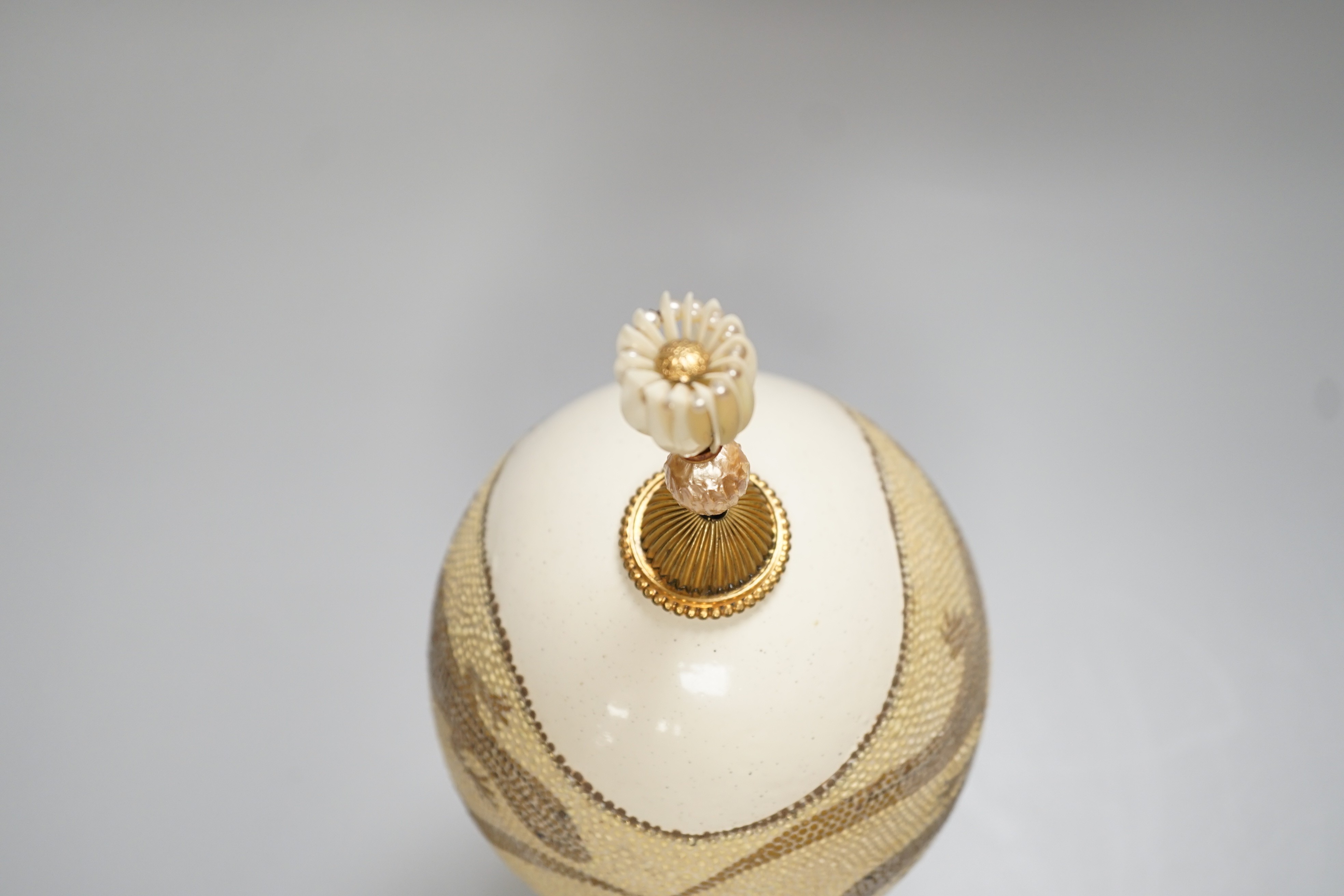 A decorated ostrich egg on gilt stand with a gilt and seed finial, 27cms high